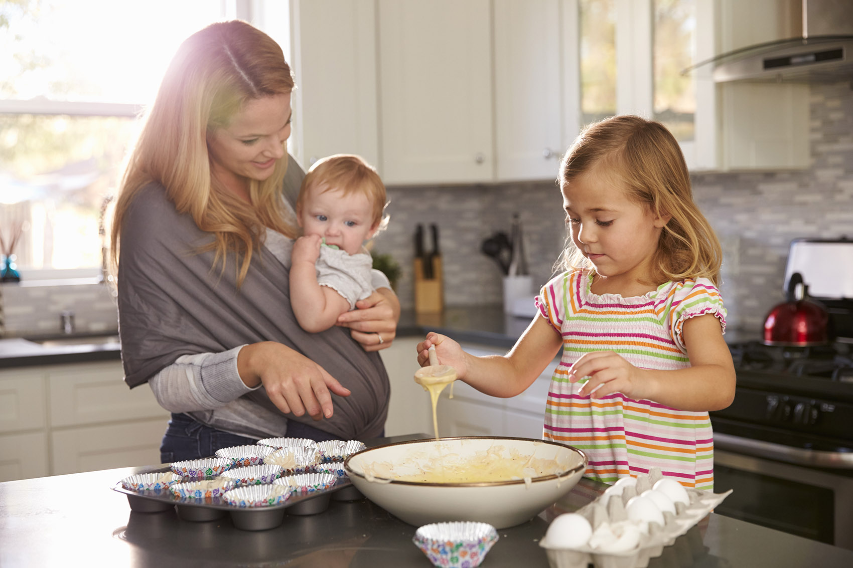 Young,girl,preparing,cake,mix,in,kitchen,,mum,showing,baby